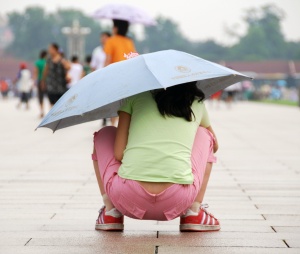 A Chinese girl ducks under an umbrella at a hutong. Photo by Sarah Orscheln.